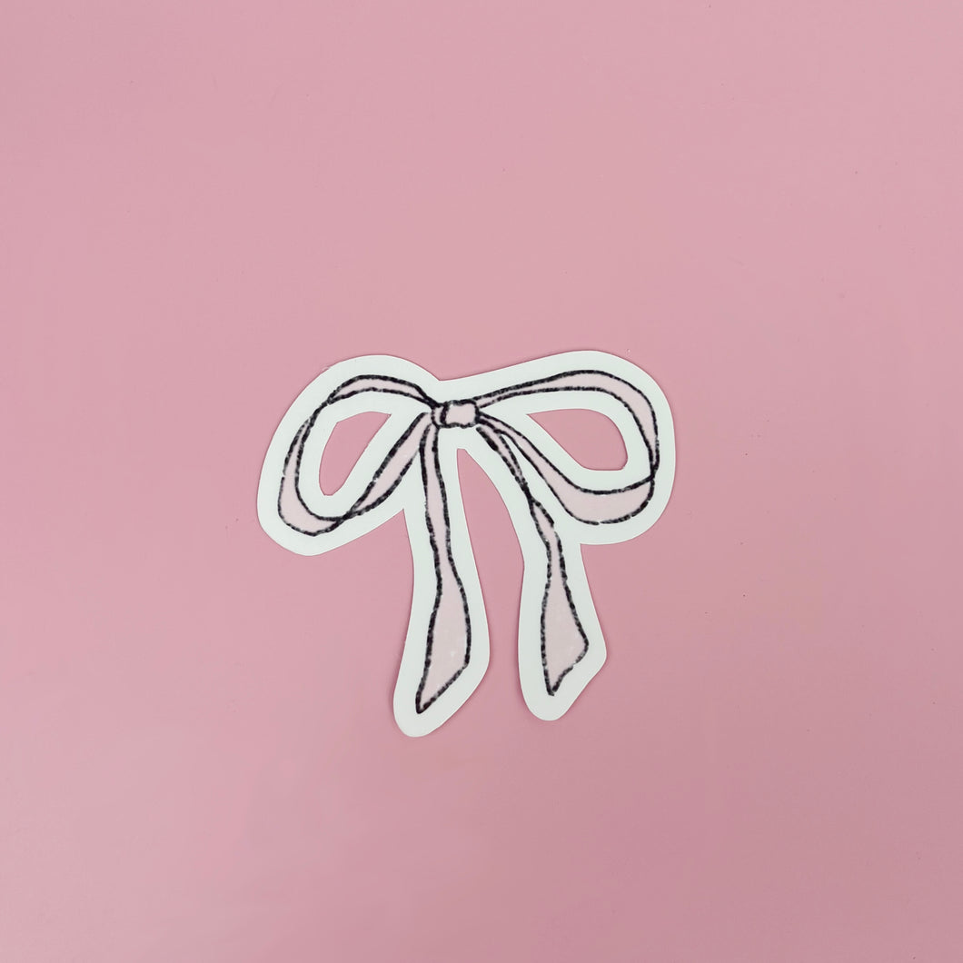 pastel pink bow / ribbon sketch that's been turned into a 6cm vinyl sticker - on a baby pink background